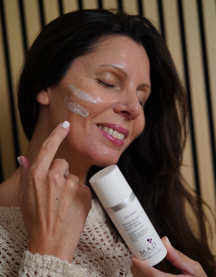 A woman applying the M.A.D Skincare on her face