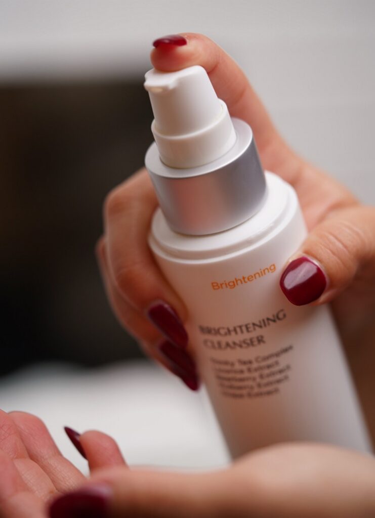 A woman holding the M.A.D Skincare Brightening Cleanser