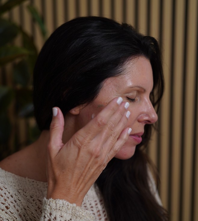 A woman applying the M.A.D Skincare Serum and Moisturizer on her face