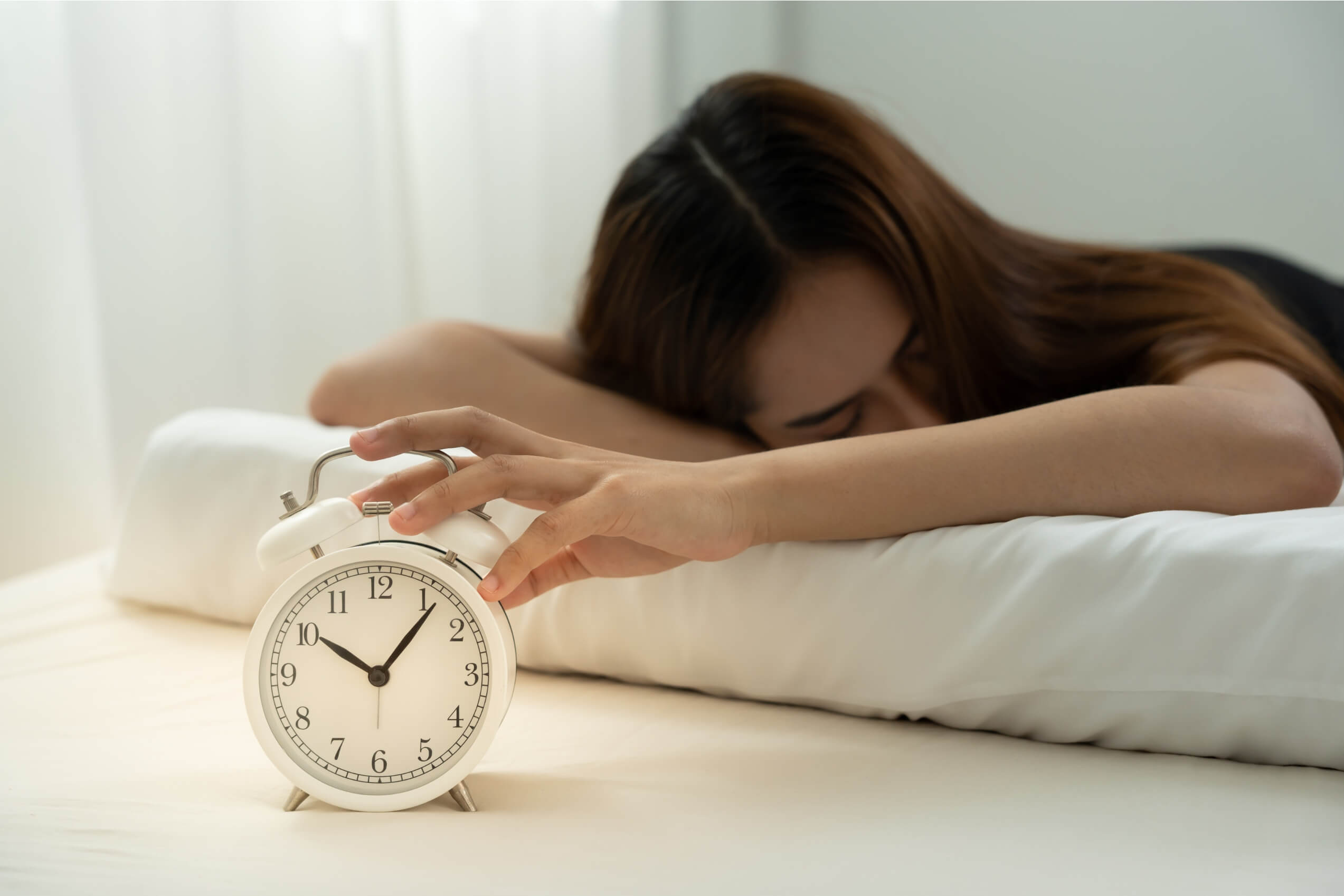 A woman placing her hand on an alarm clock