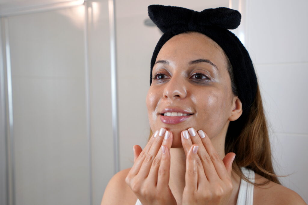 A woman applying M.A.D Skincare nourishing cleansing lotion on her face