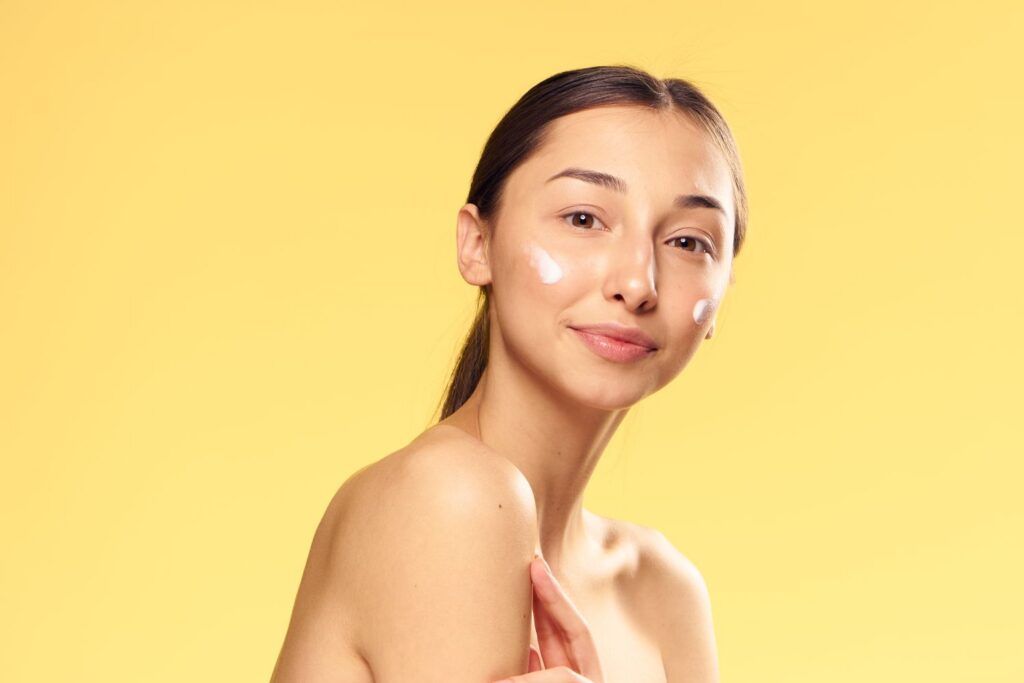 A woman applying M.A.D Skincare Moisturizer on her face
