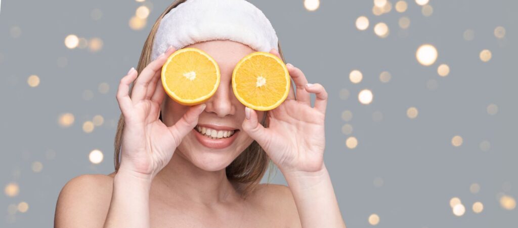 A woman holding orange slices over eyes