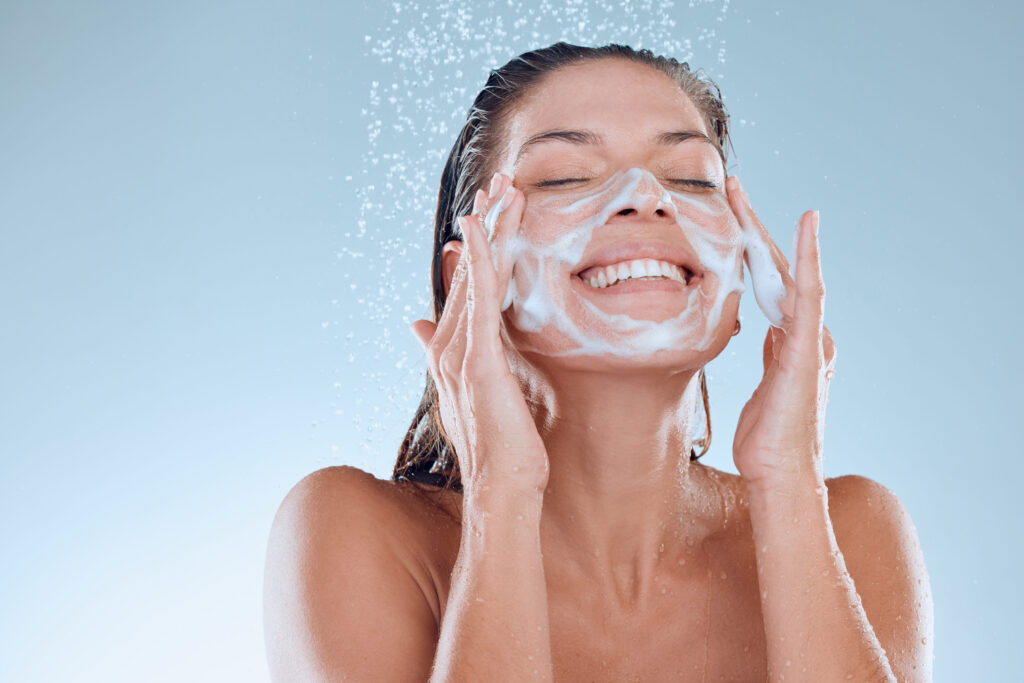 A woman applying M.A.D Skincare Nourishing Cleansing Lotion on her face